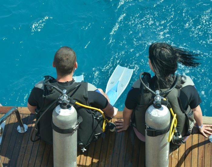 Two scuba divers preparing to dive into sea